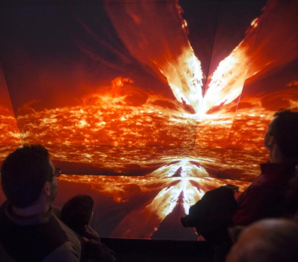 Visitantes de la exposición "Luces del Universo" ante el módulo "Caleidoscopio GTC", donde se proyectan imágenes astronómicas con efecto envolvente