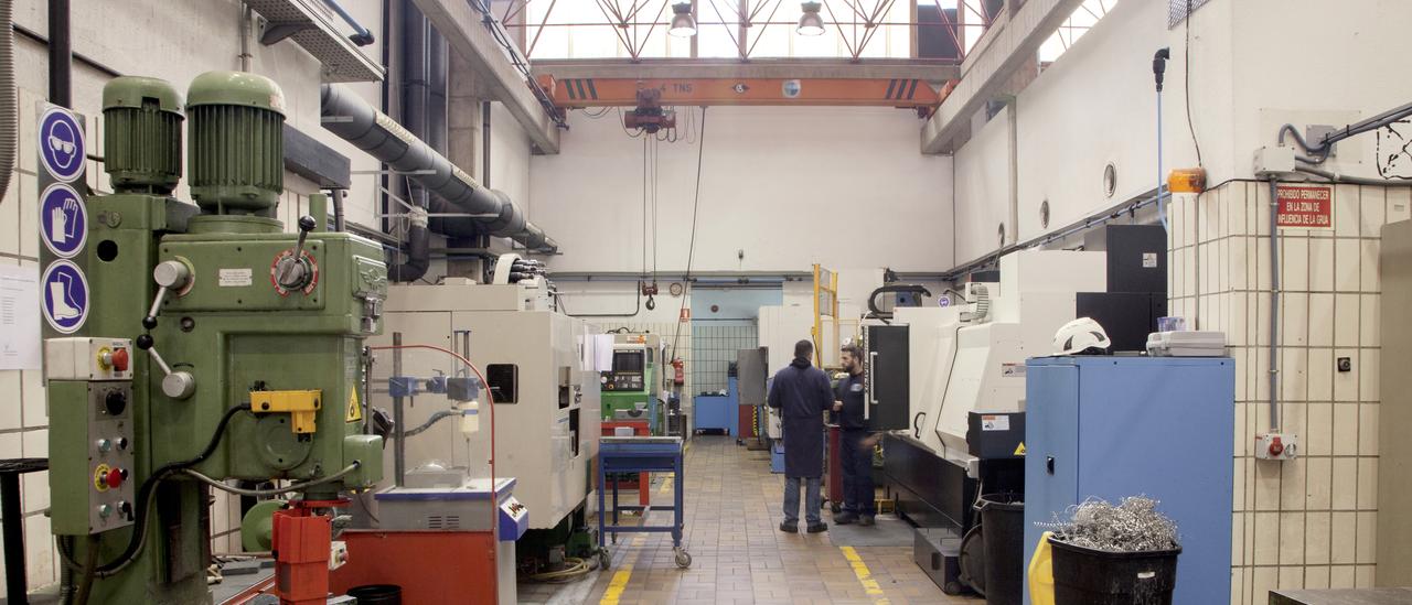 Vista de una parte del taller de mecánica con técnicos en una máquina