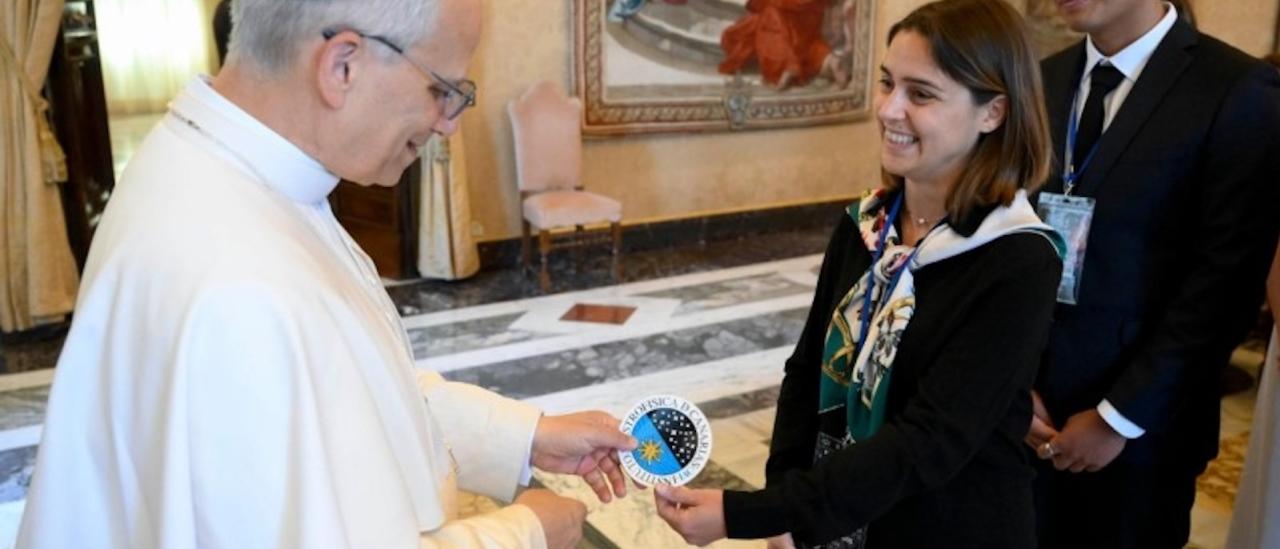 Imagen del momento en el que los doctorandos del IAC Stella Tsilia y Jun-Yan Zhang (Jerry) entregan al Papa León XIV la pegatina con el logo del IAC
