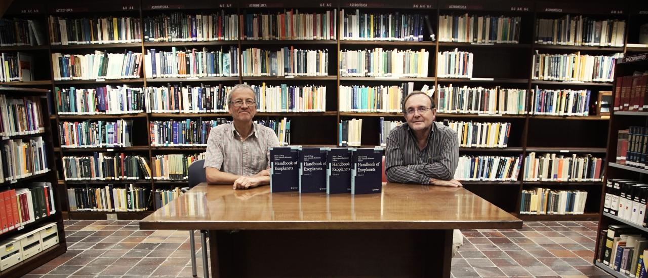 Los investigadores del IAC Hans J. Deeg y Juan Antonio Belmonte junto a los cuatro volúmenes de Handbook of Exoplanets. Crédito: Inés Bonet (IAC).