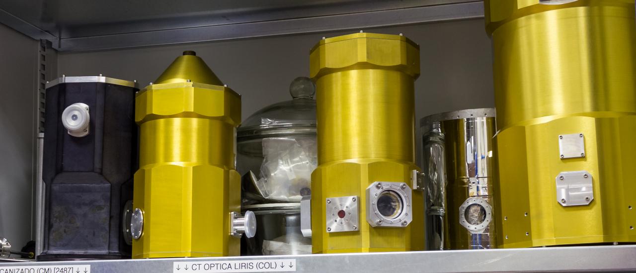 Vista general de varios criostatos de pruebas en un armario del laboratorio. Estanterías de un armario con diferentes cilindros metálicos provistos de ventanas y conectores