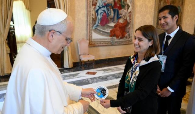 Imagen del momento en el que los doctorandos del IAC Stella Tsilia y Jun-Yan Zhang (Jerry) entregan al Papa León XIV la pegatina con el logo del IAC