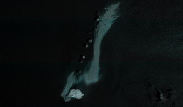 Imagen satelital en falso color del mar Arábigo en la que se aprecia una extensa mancha clara de petróleo junto al buque Caroline Bezengi y cerca de una isla del archipiélago omaní de Al Hallaniyat.