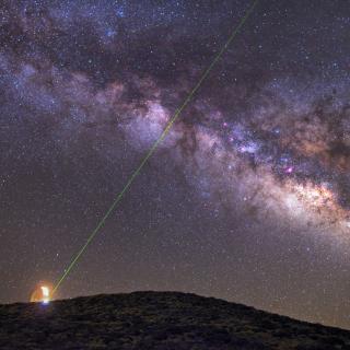 Imagen nocturna de la Vía Láctea y de la emisión de un láser verde desde la OGS durante pruebas de comunicaciones con La Palma. Autor D. López