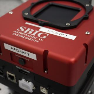 Detalle de una cámara SBIG en una mesa del laboratorio. Dispositivo de forma cúbica con conectores elctrónicos