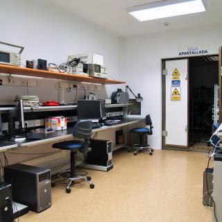 General view of the Electromagnetic Compatibility Laboratory with workbenches and computers and view in the background of the entrance to the shielded room