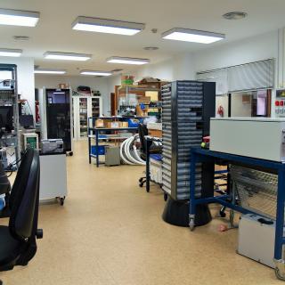 Vista general del laboratorio de diseño electrónico Vista general del laboratorio de diseño electrónico con varios bancos de trabajo, racks de electrónica y armarios para componentes y piezas electrónicas