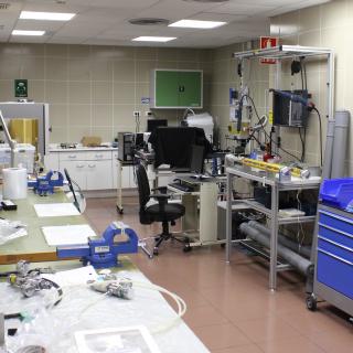 Vista general del laboratorio de integración mecánica. Laboratorio de tamaño mediano con bancos de trabajo, aparatos electrónicos, herramientas mecánicas y armarios
