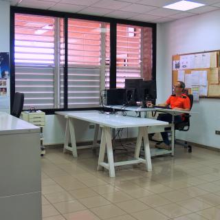 Vista de una parte del taller de delineación con un técnico en una mesa trabajando frente a un ordenador